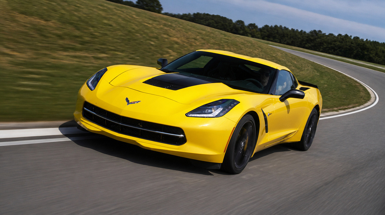 Gelber Sportwagen Chevrolet Corvette fährt auf kurviger Landstraße bei Tageslicht.