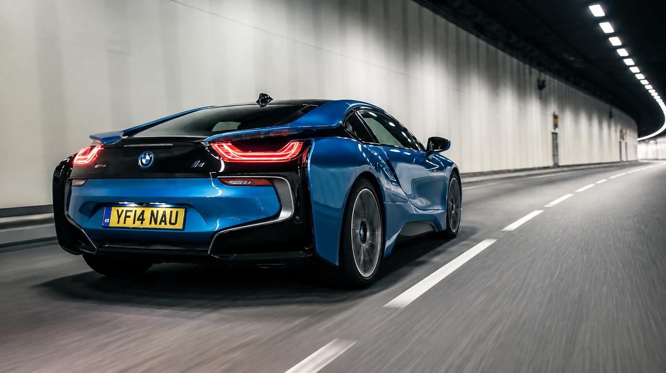 Blauer BMW i8 fährt in gut beleuchtetem Tunnel auf asphaltierter Straße mit weißen Fahrbahnmarkierungen.