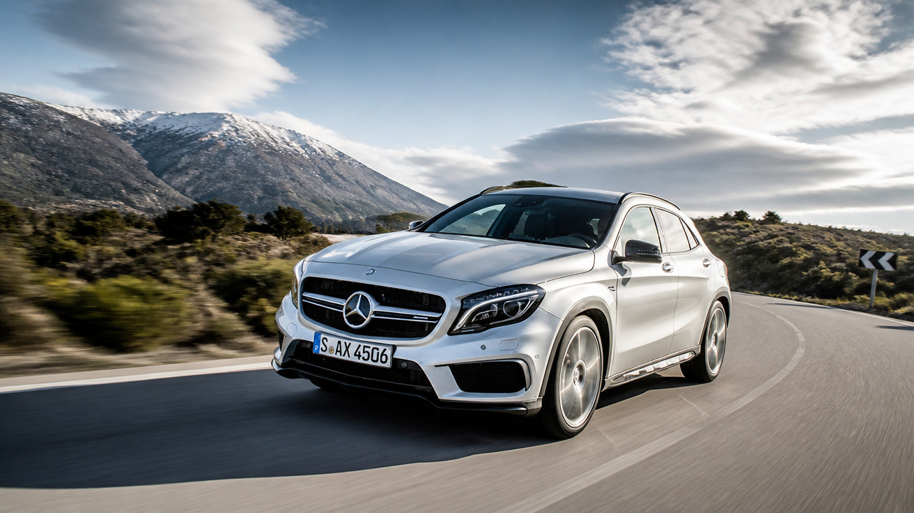 Silberner Mercedes-Benz SUV fährt auf kurviger Bergstraße mit schneebedeckten Gipfeln im Hintergrund.